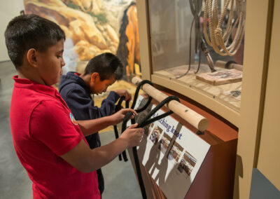 two school boys look and learn how to tie and lasso ropes in the Abe Hays gallery
